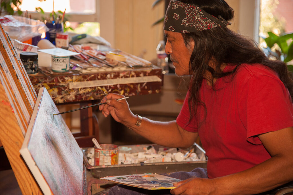 Shonto Begay painting in his art studio. Native American Navajo Diné artist Shonto Begay